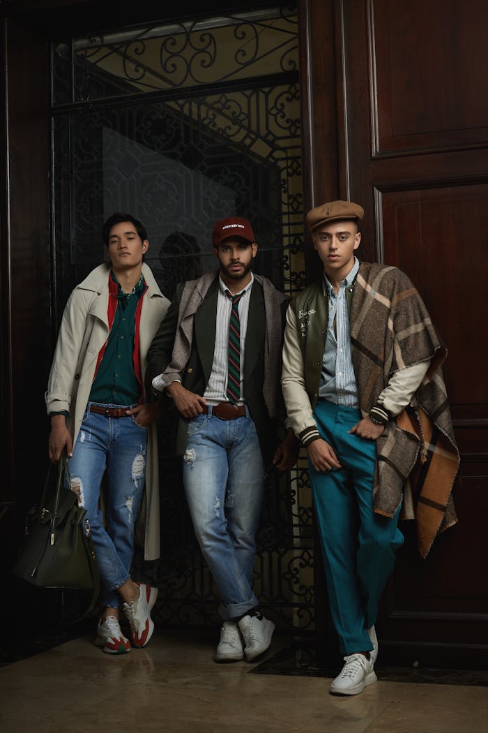 Three stylish men pose indoors in trendy casual attire, highlighting modern fashion trends.