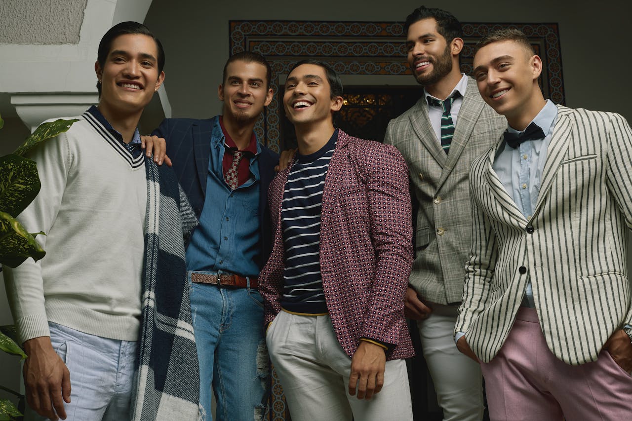 services-04 Five men in fashionable attire posing indoors, exuding confidence and style.