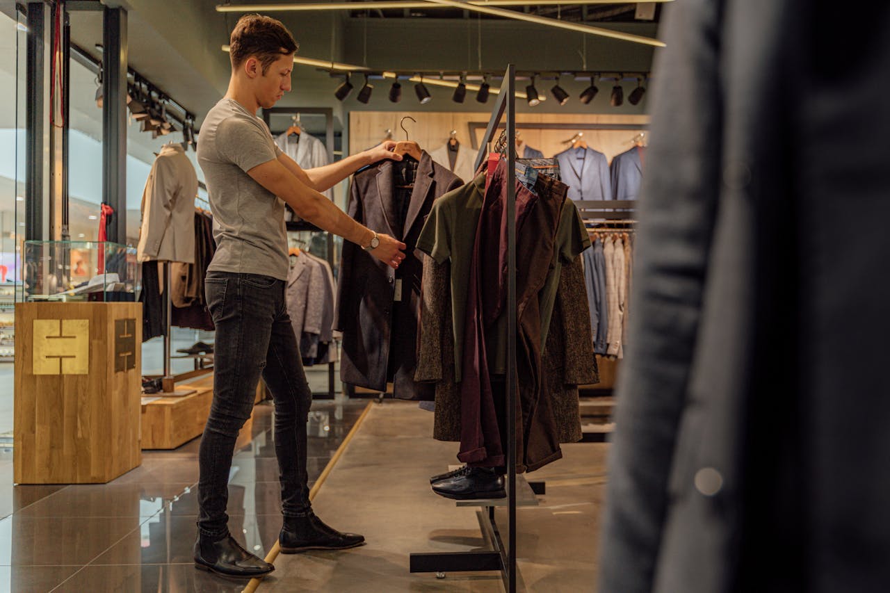 services-03 A man browsing stylish blazers in a modern clothing store, focusing on men's fashion.